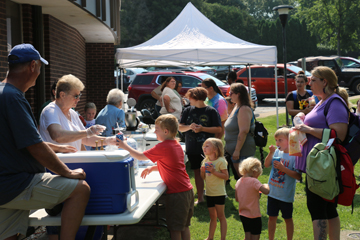 Church member Toi Nicolet serves up snow cones to a line of kids.